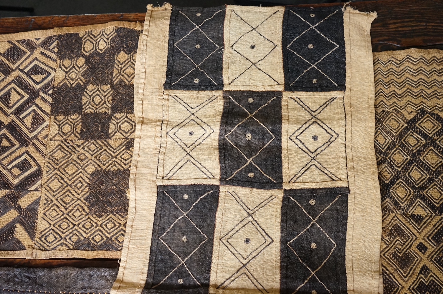 A collection of five 20th century African Congo hand woven and embroidered raffia palm leaf runners and mats, together with a later large printed hanging. 260cm x 138cm. Condition - one smaller mat has a hole in the weav